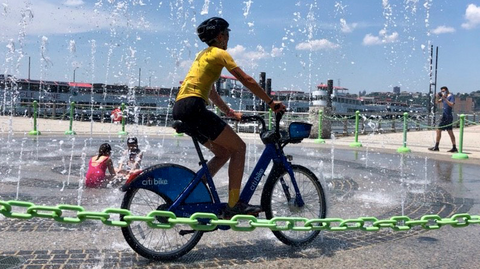 Micah rides the citi bike through a fountain 